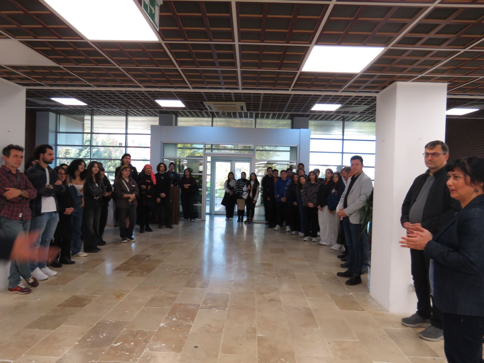 Sergi açılışında konuşmalar yapılıyor. Sergi salonunda öğrenciler ve akademisyenler görünmektedir.