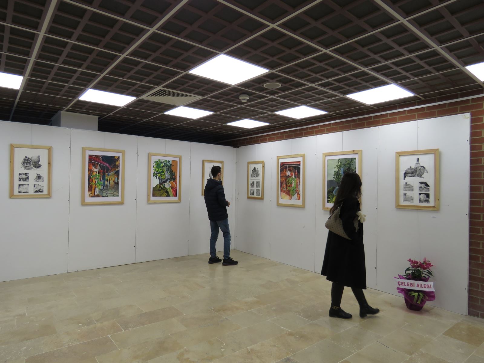 İki izleyici sergideki resimleri inceliyor.