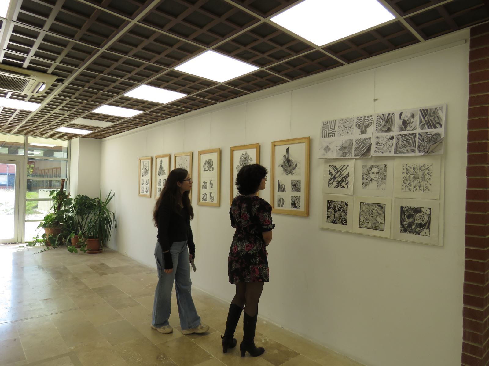 İki izleyici sergideki resimleri inceliyor.